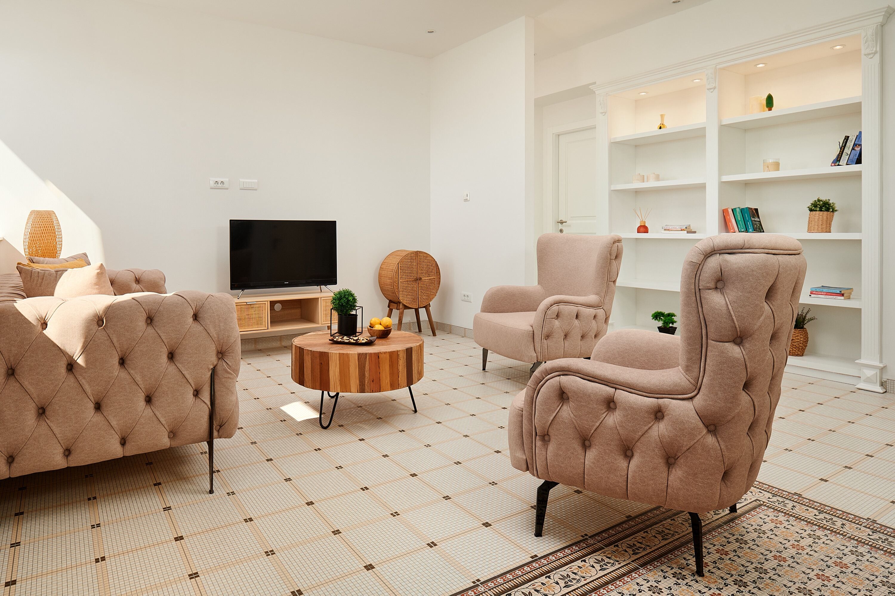 A modern living room with a tufted sofa, a round coffee table, and a television.
