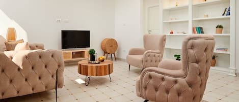 A modern living room with a tufted sofa, a round coffee table, and a television.