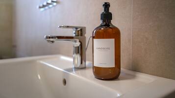A bathroom sink with a bottle of hand soap labeled "HANDSEIFE HAND SOAP" on the counter.