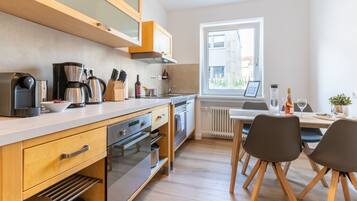 A modern kitchen with wooden cabinets, stainless steel appliances, and a dining area with a table and chairs.