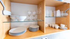 Una cocina con armarios de madera, estantes de vidrio y platos y tazas blancos.