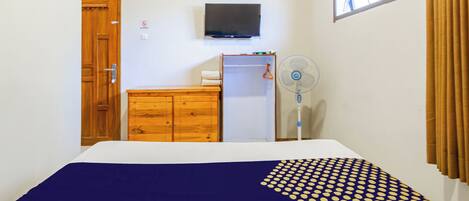 Un dormitorio con cama, cómoda de madera, televisor y ventana con cortinas.