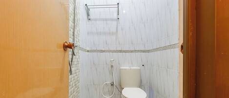 A bathroom with a toilet, a shower, and a tiled floor.