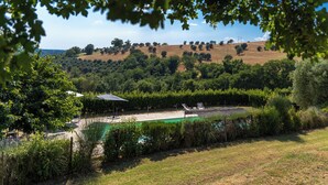 A pool area with lounge chairs, surrounded by greenery and a hilly landscape in the background. - Scappo in Umbria, Dolce Godera (LUGNANO IN TEVERINA)