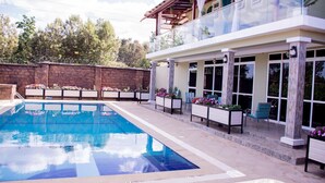 Ein modernes Haus mit Swimmingpool, Sitzgelegenheiten im Freien und einem Balkon.