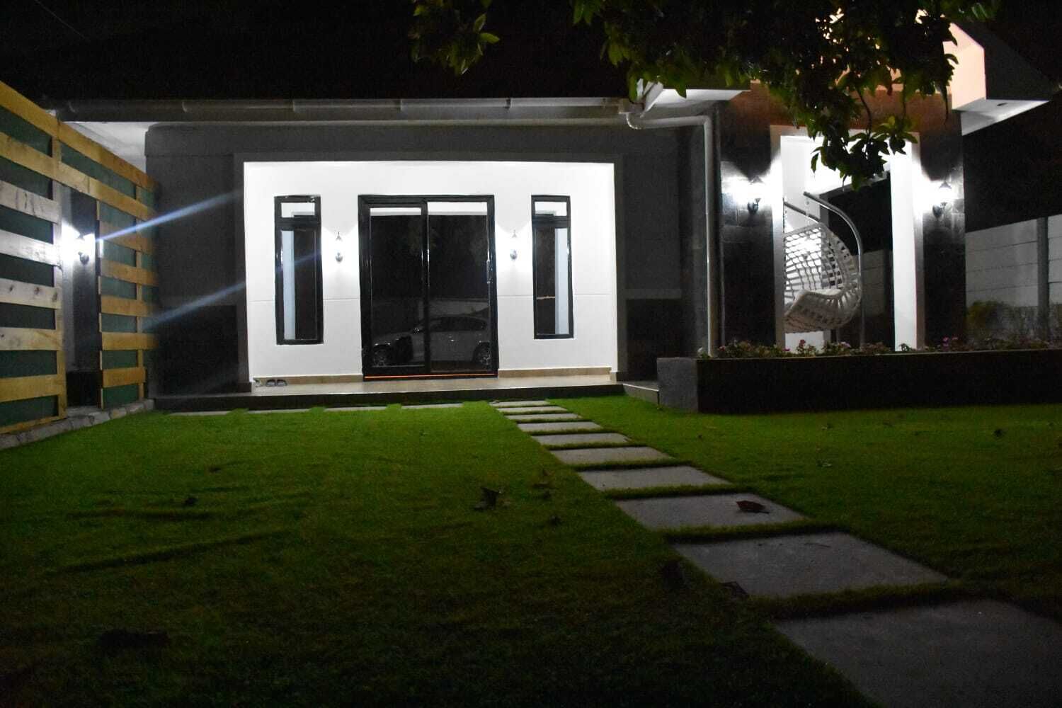 Ein modernes Haus mit gepflegtem Rasen, befestigter Auffahrt und einem großen Fenster mit einer Schiebetür.