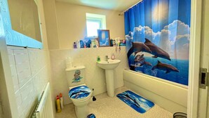 Une salle de bain équipée de toilettes, d’un lavabo et d’un rideau de douche orné de motifs de dauphins.