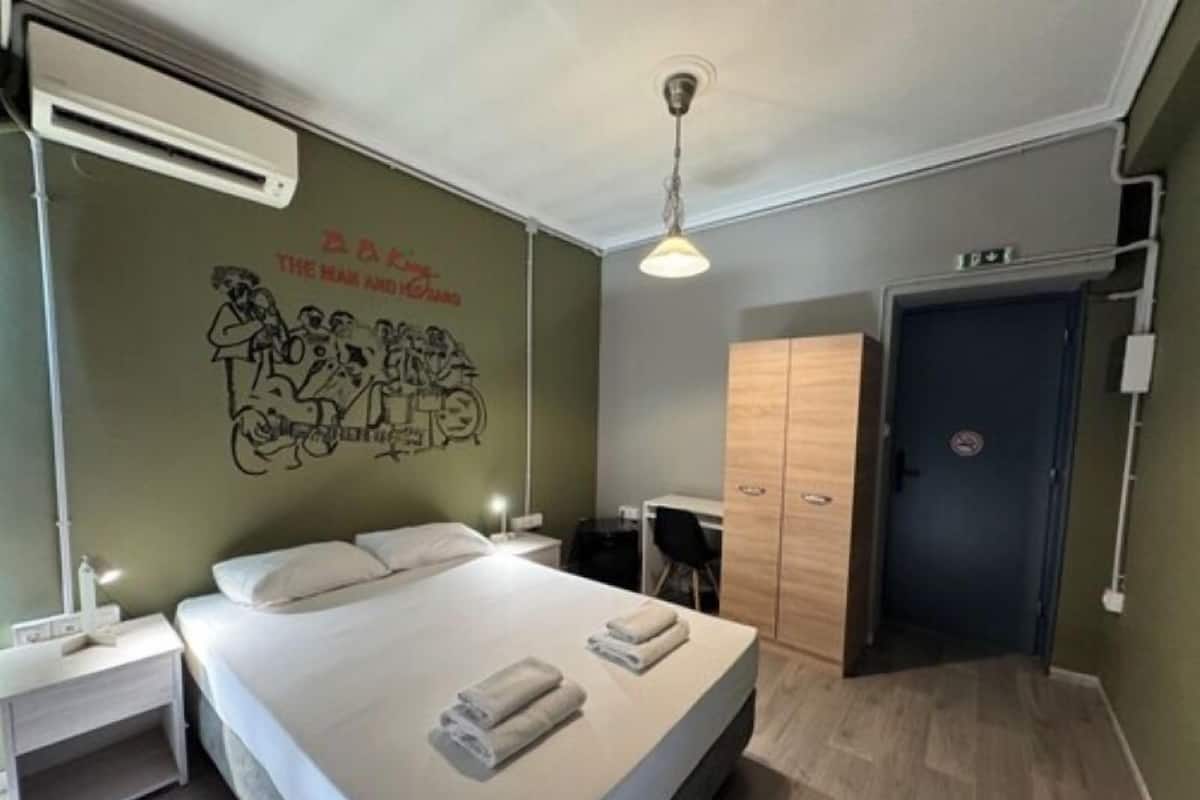 Une chambre d’hôtel comprenant un lit, un bureau, une armoire et un mur orné d’une fresque.