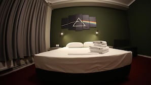 A hotel room with a large bed, a wall art piece, and a window with curtains.