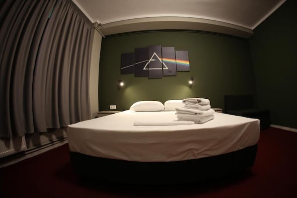 A hotel room with a large bed, a wall art piece, and a window with curtains.