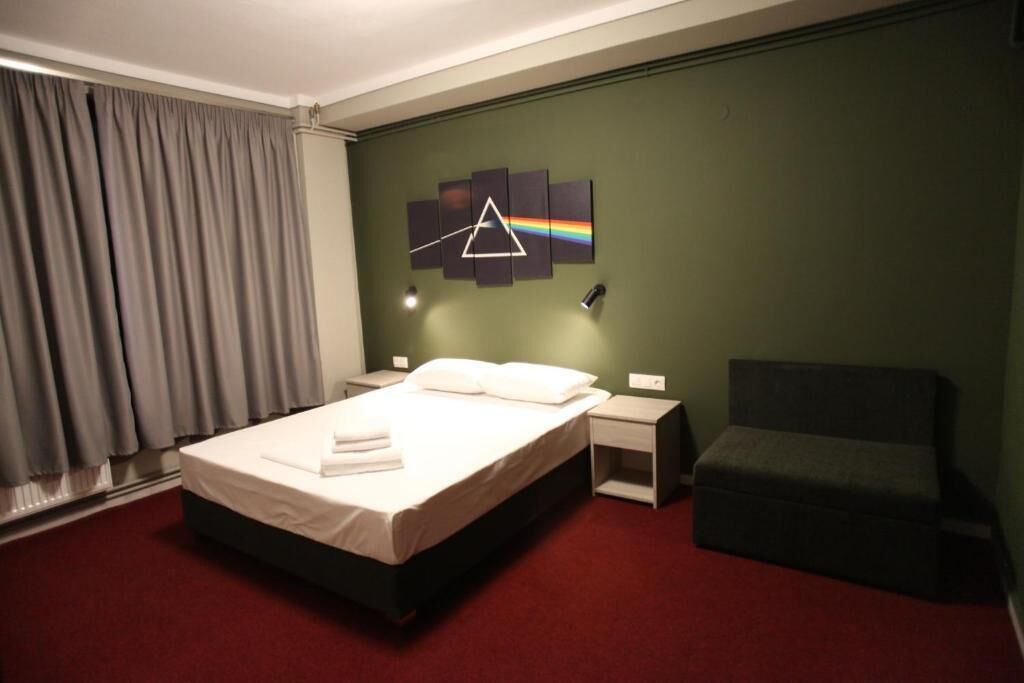 Une chambre d’hôtel comprenant un lit, une table de chevet, une chaise et une œuvre d’art murale.