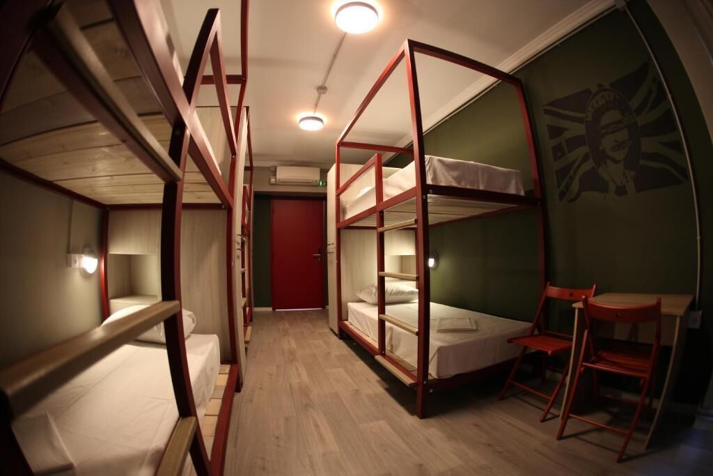 A dormitory room with bunk beds, a desk, and a chair.