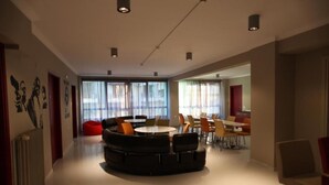 A modern interior with a circular seating area, large windows, and a dining space.