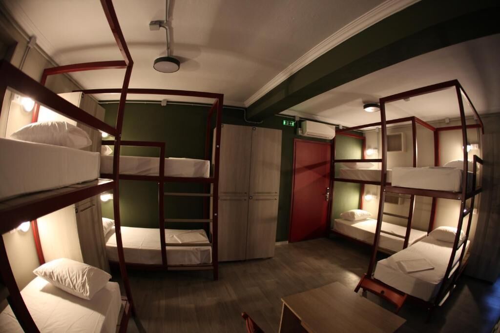 A bunk room with bunk beds arranged in a circular layout, a wardrobe, and a door.