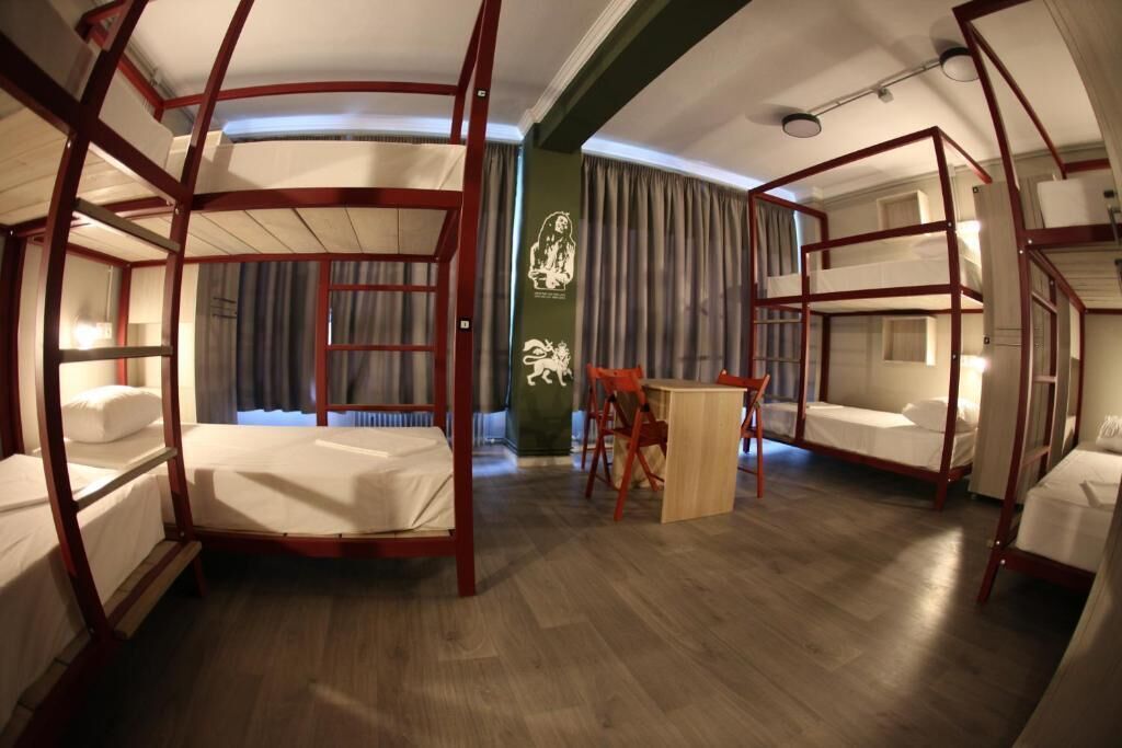 A room with four bunk beds, a wooden table, and a chair.