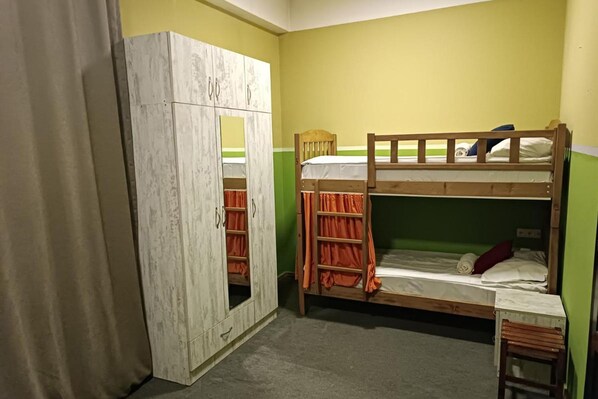 A room with bunk beds, a wardrobe, and a small table.