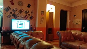 A living room with a television, leather sofas, and a wall decorated with photos and memorabilia. - Museum Hostel (Tbilisi)