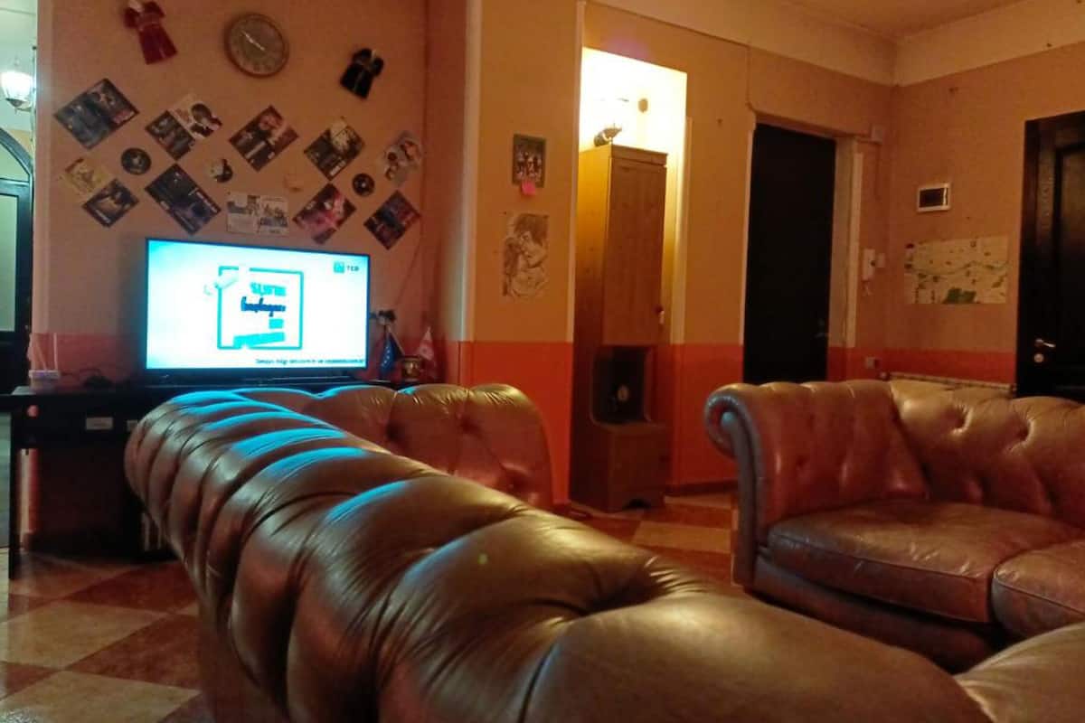 A living room with a television, leather sofas, and a wall decorated with photos and memorabilia.