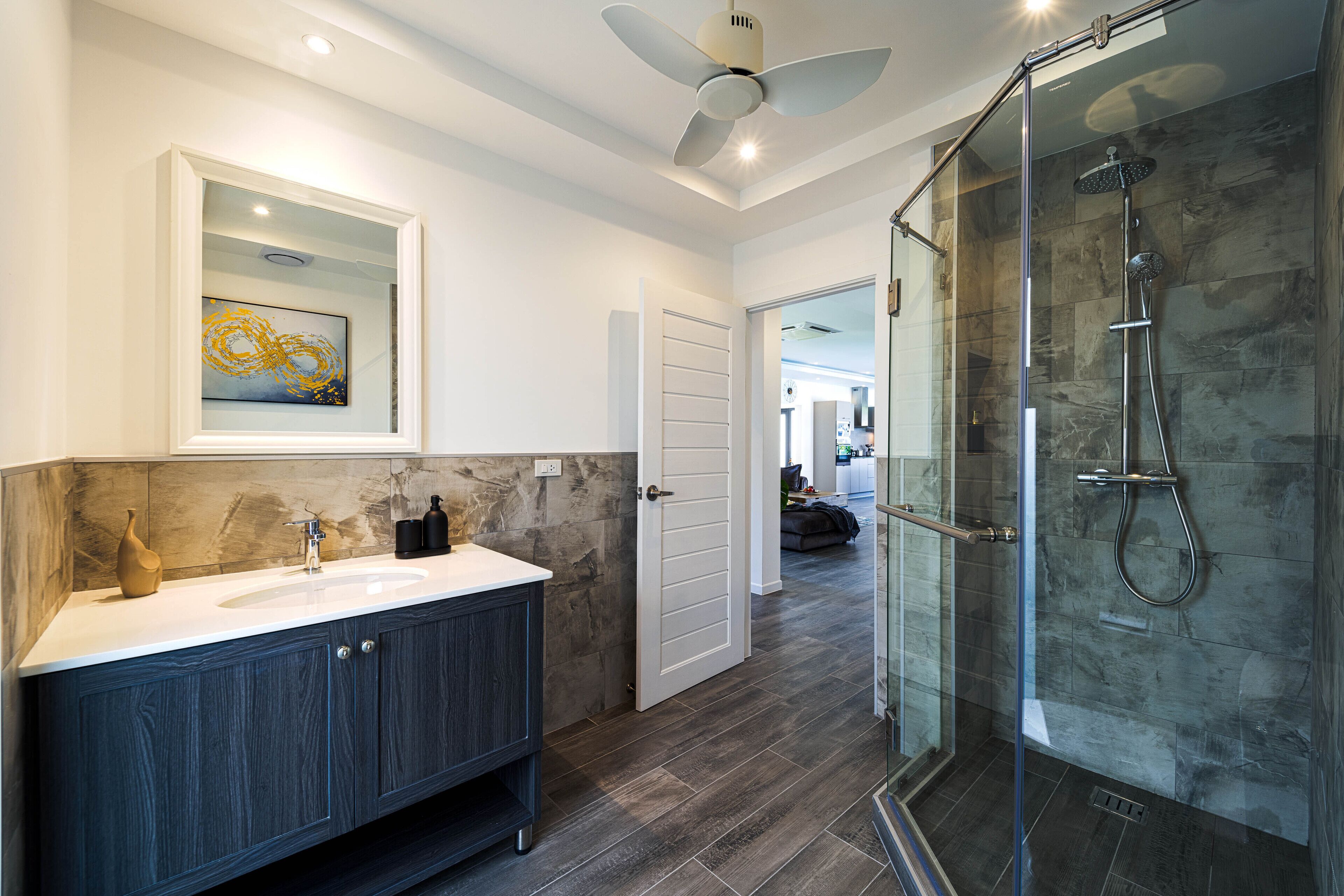 A modern bathroom with a glass shower enclosure, a vanity with dark wood cabinets, and a white countertop.