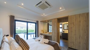 A modern hotel room with a large bed, a bathroom with a mirror, and a view of the outdoors. - Modern 3 Bedroom Private Pool Villa -ML7 (Hua Hin)