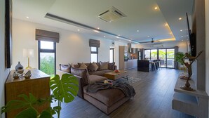 A spacious living area with a large brown sofa, a coffee table, and a dining area in the background. - Modern 3 Bedroom Private Pool Villa -ML7 (Hua Hin)