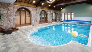 Uma piscina interior com paredes de pedra e vigas de madeira.