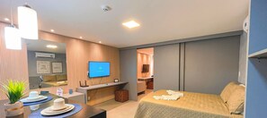Een hotelkamer met een bed, een bureau, een televisie en een kleine kitchenette.