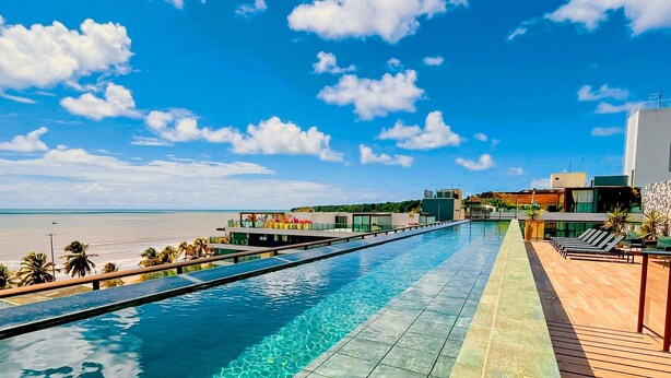 Ein langer Swimmingpool mit Blick auf Strand und Meer.