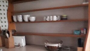 A kitchen with white cabinets, a countertop, and shelves above holding various kitchenware.