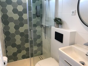 A modern bathroom with a glass shower enclosure, a white sink, and a hexagonal tile backsplash. - Quiet Waterloft Near Amsterdam and Schiphol Ws11 (Aalsmeer)