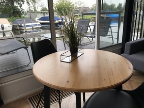 A round wooden table with a potted plant in the center, surrounded by black chairs. - Quiet Waterloft Near Amsterdam and Schiphol Ws11 (Aalsmeer)