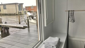 Una habitación con vista a un muelle y barcos, una ventana con una toalla y un radiador.
