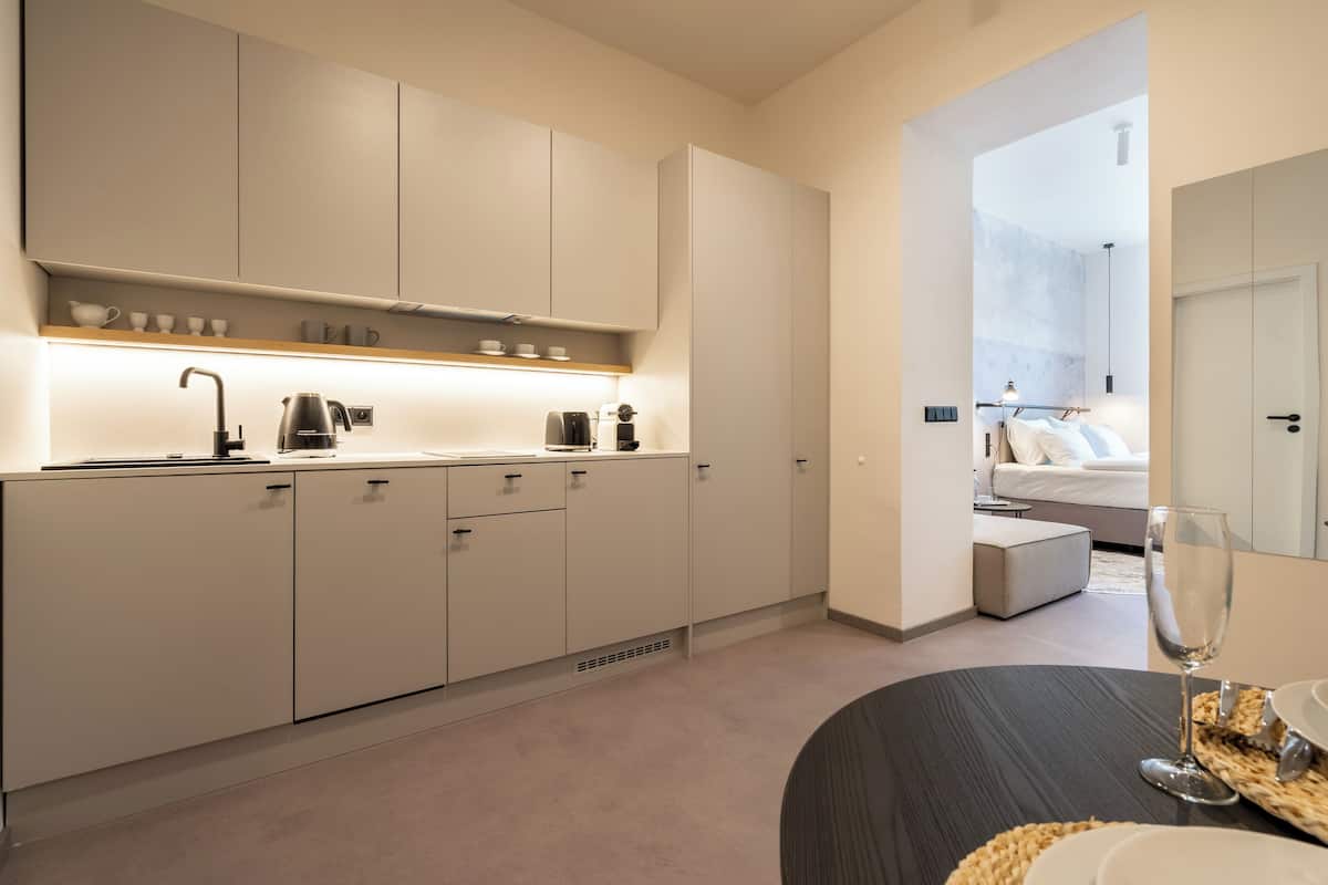A modern kitchen with white cabinets, a countertop, and a dining area with a table set for two.
