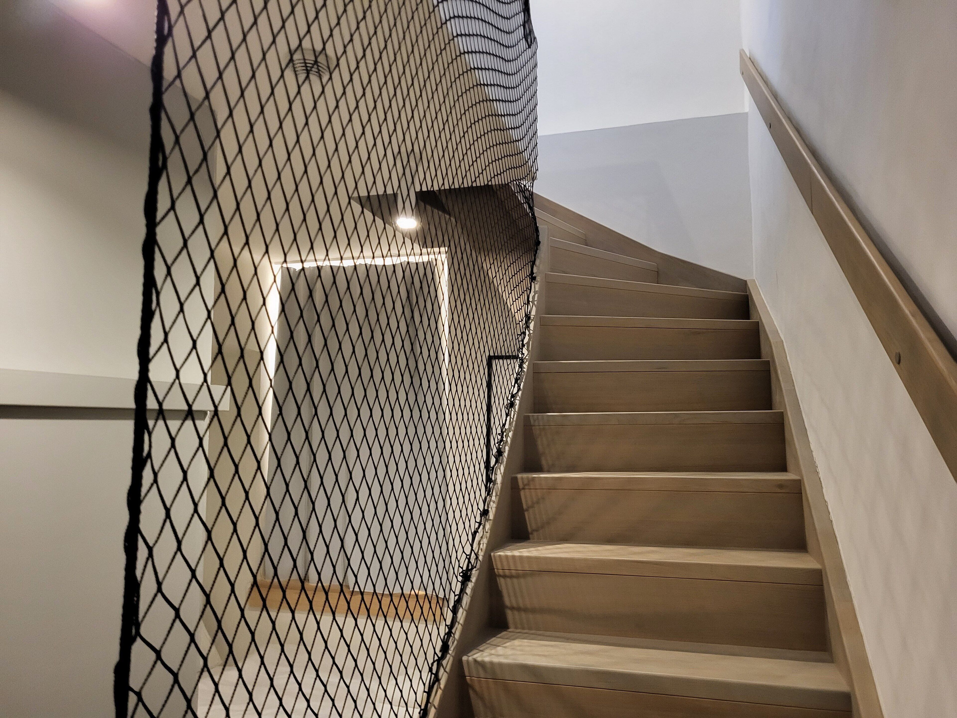 Eine Holztreppe mit einer schwarzen Netzsicherheitsbarriere.