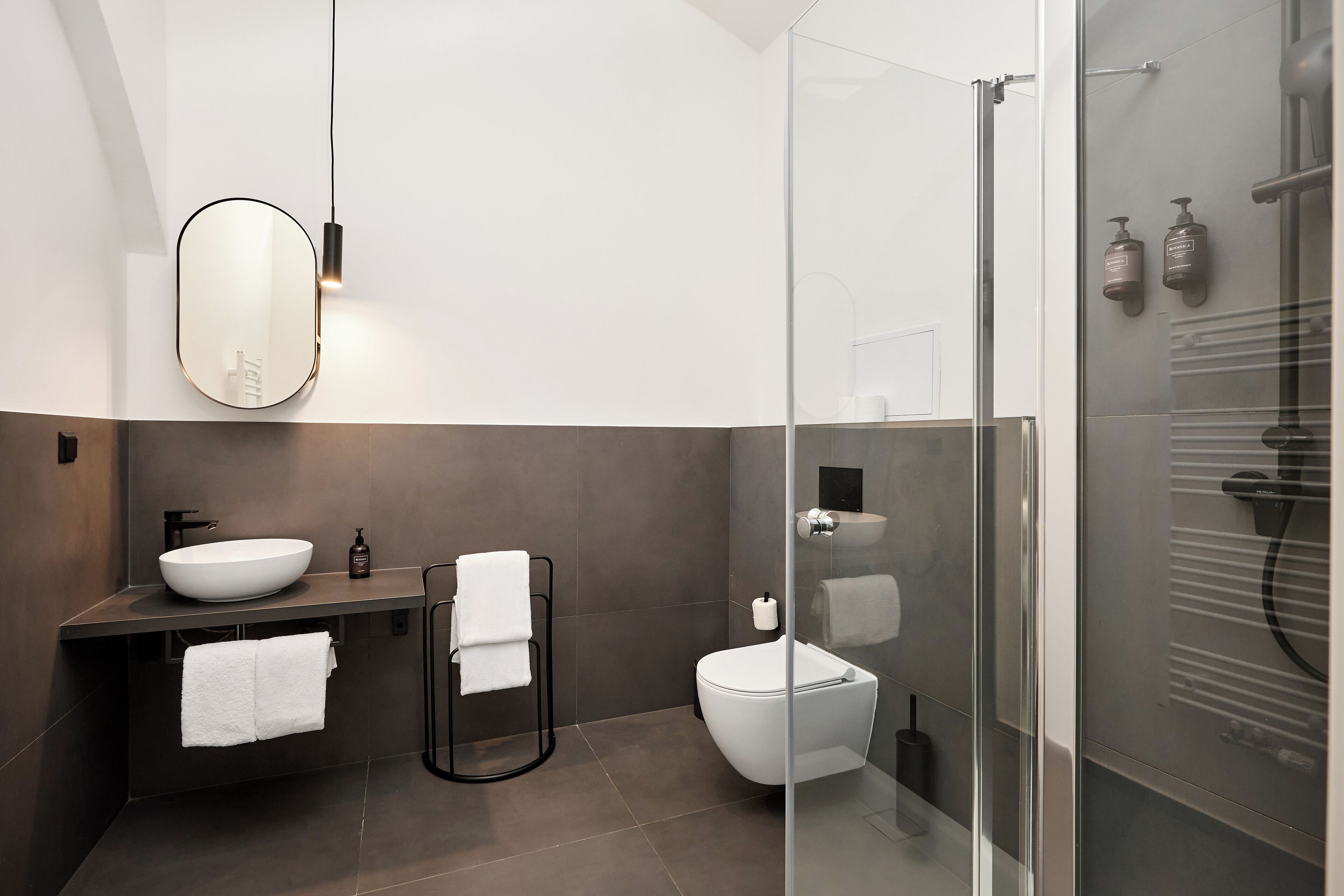 A modern bathroom with a large oval sink, a glass shower enclosure, and a toilet.