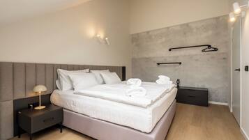 A modern bedroom with a bed, bedside table, and wall-mounted towel rack.
