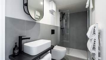 Une salle de bain moderne avec un lavabo blanc, un robinet noir et une douche à parois de verre.