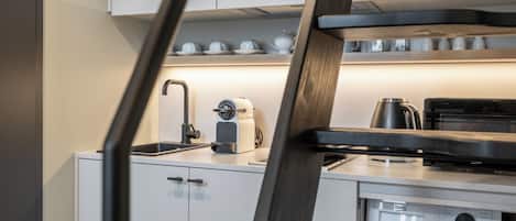 A modern kitchen with white cabinets, a coffee maker, a kettle, and a microwave.