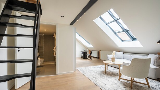 Een modern loft appartement met dakraam, trap, bank en salontafel.