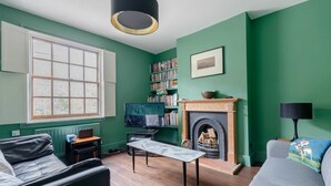 A living room with a fireplace, a bookshelf, a television, and a sofa. - Trendy 2BD House 5 Mins From Willesden Junction! (London)