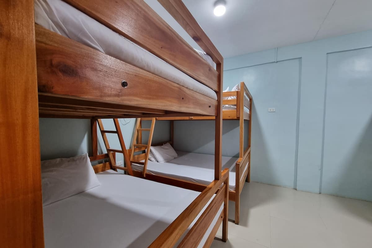 Dormitorio con literas de madera y ropa blanca.