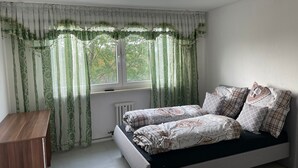 Une chambre à coucher avec un lit, une table de chevet et une fenêtre avec des rideaux.