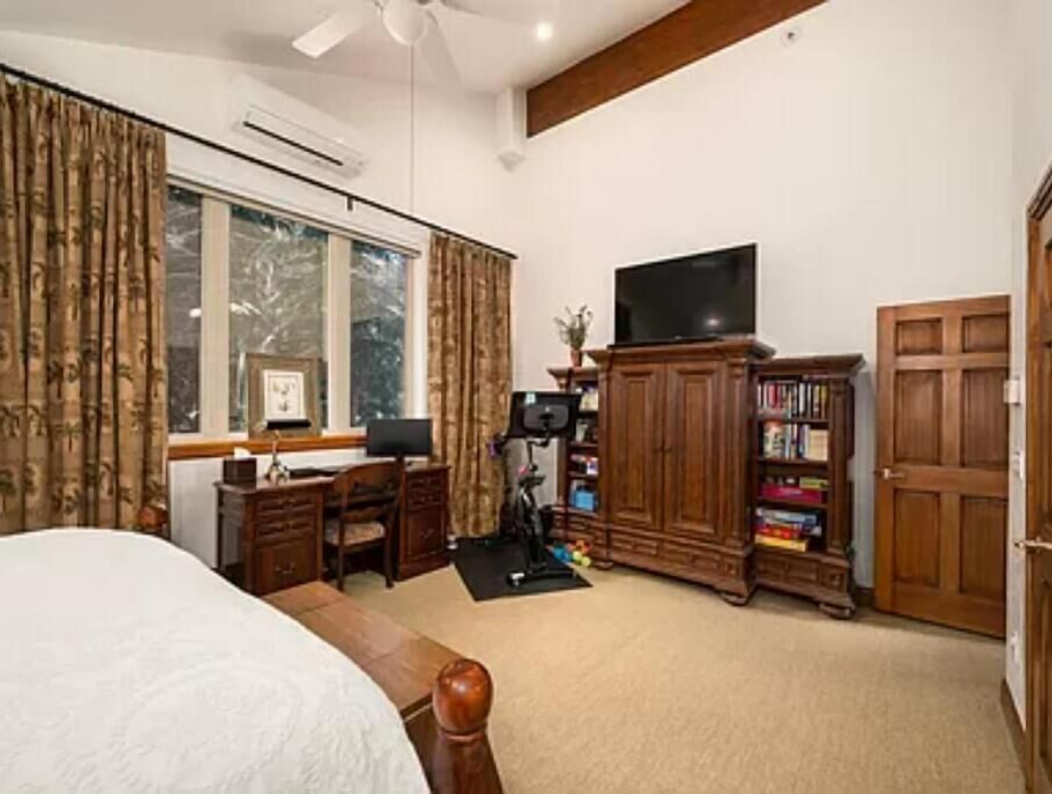 Un dormitorio con cama, escritorio, televisor y estantería.