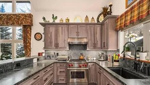 Una cucina moderna con mobili in legno, una cappa in acciaio inossidabile e un piano di lavoro in granito.