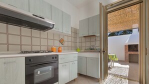 Moderni keittiö, jossa on vaaleat kaapit, kaasuliesi ja sisäänrakennettu uuni.