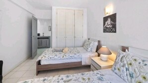 A bedroom with two beds, a nightstand, a wall-mounted lamp, and a framed picture of London. - Spacious central beach home steps from the sea (Carvoeiro)