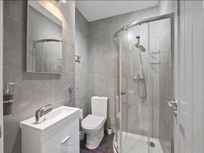 Une salle de bain moderne avec une douche à parois de verre, un lavabo blanc et des toilettes.