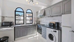 A modern kitchen with grey cabinets, a built-in washing machine, and a microwave. - Spacious central beach home steps from the sea (Carvoeiro)