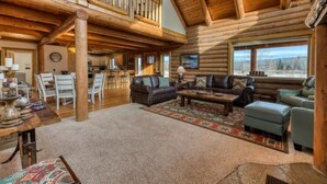 A spacious log cabin interior with a high ceiling, a dining area, and a cozy living room with a fireplace. - ********River Cabin Minutes To Town***** (Hamilton)