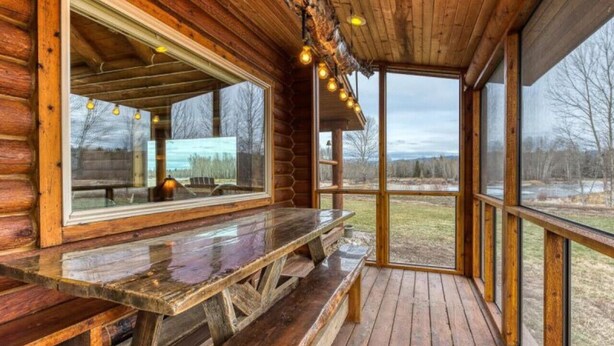 A wooden cabin with a wooden deck, a bench, and a large window overlooking a landscape. - ********River Cabin Minutes To Town***** (Hamilton)